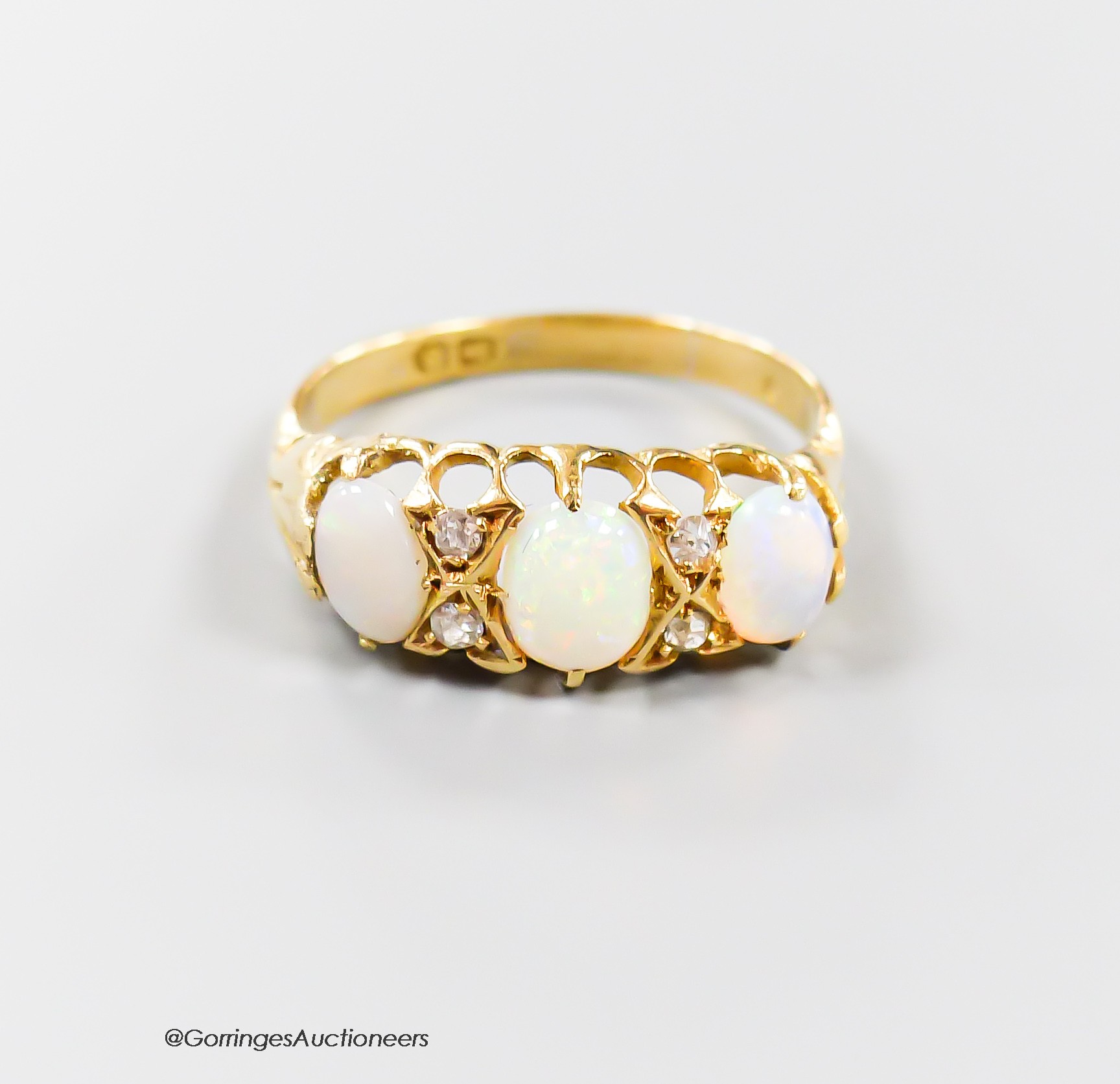 An Edwardian yellow metal, three stone opal and four stone diamond chip set half hoop ring, size Q/R, gross 3.5 grams.